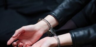 Hands in handcuffs resting on a dark surface