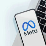 Meta logo on smartphone next to laptop keyboard.