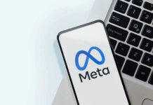 Meta logo on smartphone next to laptop keyboard.