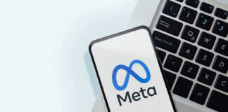 Meta logo on smartphone next to laptop keyboard.