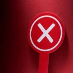 Red sign with a white cross symbol on a dark background