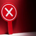 Red sign with a white 'X' symbol against a dark background