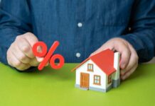 Person holding a percentage symbol above a model house