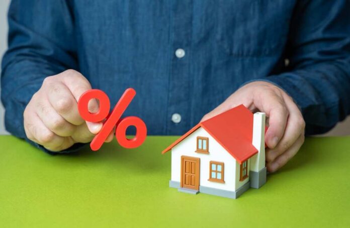 shutterstock_2672764475.jpg Person holding a percentage symbol above a model house