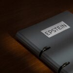 A gray folder labeled 'EPSTEIN' resting on a wooden surface