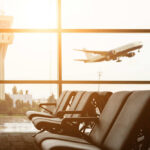 View of an airport terminal with an airplane taking off in the background