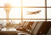 View of an airport terminal with an airplane taking off in the background