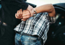 Person in handcuffs arrested by police officer.