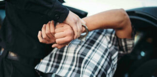 Person in handcuffs arrested by police officer.