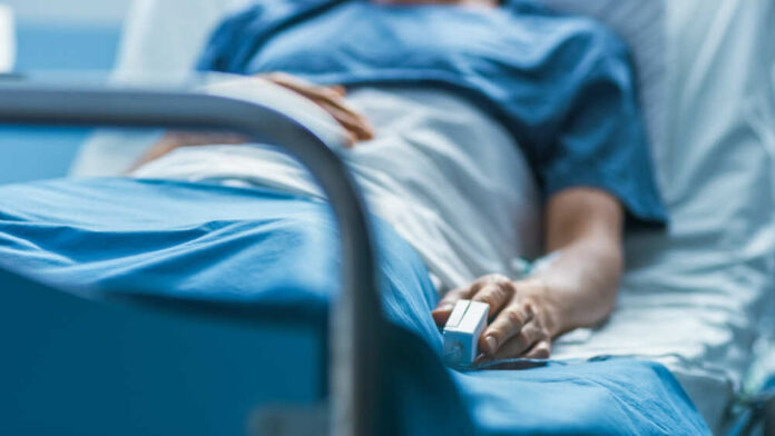 A patient lying in a hospital bed with a monitoring device in hand