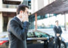 Security personnel in a suit communicating via earpiece near a car