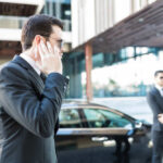 Security personnel in a suit communicating via earpiece near a car