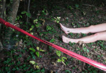 Bare feet visible near caution tape in a wooded area