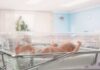 Newborn baby lying in a transparent crib in a hospital nursery