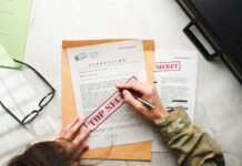 A person in military attire marking a classified document with a red 'FOR SECRET' stamp