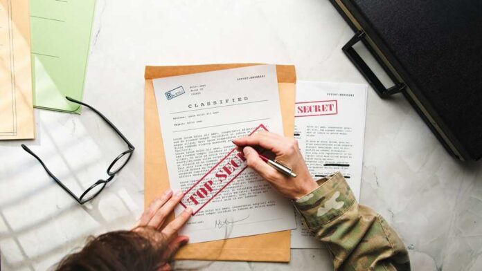 A person in military attire marking a classified document with a red 'FOR SECRET' stamp