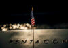 American flag above engraved Pentagon sign at night