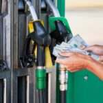 Person holding cash at a gas station while preparing to refuel