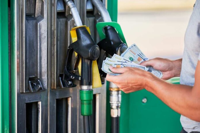 Person holding cash at a gas station while preparing to refuel