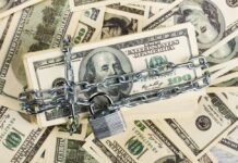 A stack of hundred dollar bills secured with a chain and padlock