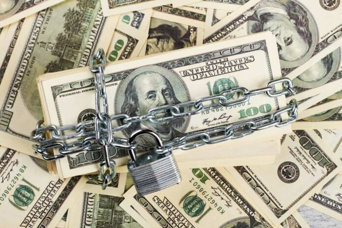 A stack of hundred dollar bills secured with a chain and padlock
