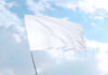 White flag waving against blue sky background.
