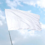 White flag waving against blue sky background.