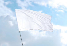 White flag waving against blue sky background.