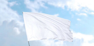 White flag waving against blue sky background.