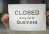 Grocery Giant COLLAPSES — Feds Killed It! A person holding a sign that reads 'CLOSED Going Out of Business'