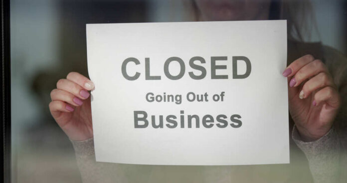 A person holding a sign that reads 'CLOSED Going Out of Business'
