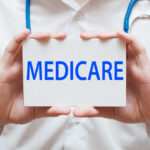 A medical professional holding a sign that says MEDICARE