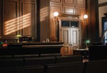 Interior of a courtroom with wooden paneling and green desk lamp