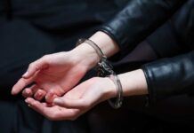 Hands in handcuffs resting on a dark surface