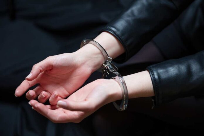 Hands in handcuffs resting on a dark surface