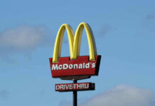 McDonalds drive-thru sign against a blue sky.