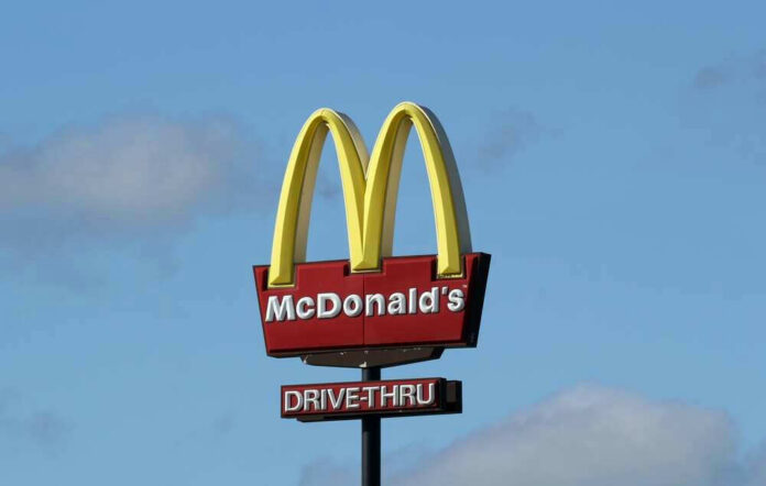 McDonalds drive-thru sign against a blue sky.