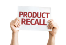 Hands holding a sign that reads 'PRODUCT RECALL'