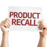 Hands holding a sign that reads 'PRODUCT RECALL'