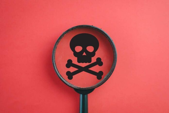 Magnifying glass focusing on a skull and crossbones symbol against a red background