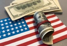 A roll of hundred dollar bills placed on an American flag