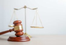 A wooden gavel in front of a balance scale symbolizing justice