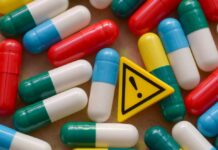 Colorful capsules scattered around a yellow warning sign