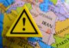 A yellow warning sign placed on a map highlighting Iran