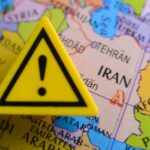 A yellow warning sign placed on a map highlighting Iran