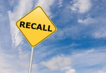 Drinks RECALLED — Hidden Allergen Threat Yellow sign with RECALL text against blue sky.