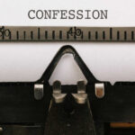 Close-up of a typewriter with the word 'CONFESSION' typed on paper
