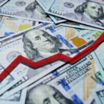 A pile of hundred dollar bills with a red upward trend line overlay