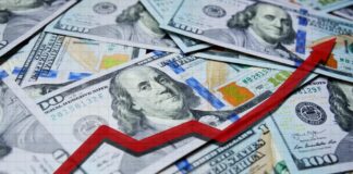 A pile of hundred dollar bills with a red upward trend line overlay