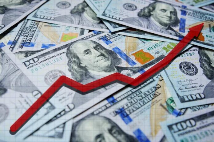 A pile of hundred dollar bills with a red upward trend line overlay